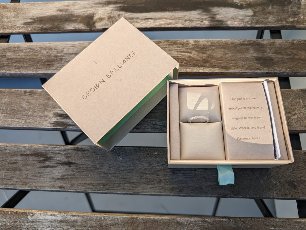 Our Grown Brilliance eternity ring in its packaging on a wooden table