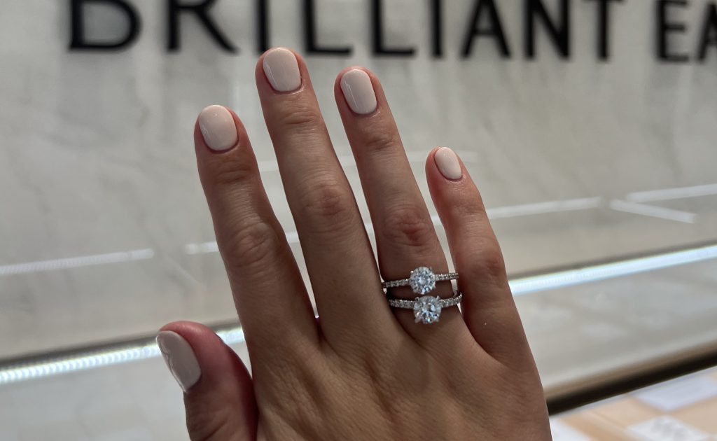 Two diamond rings being compared on a hand in a Brilliant Earth showroom