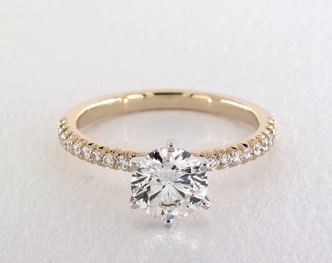 Round diamond with white-metal prongs on a yellow-gold pave band
