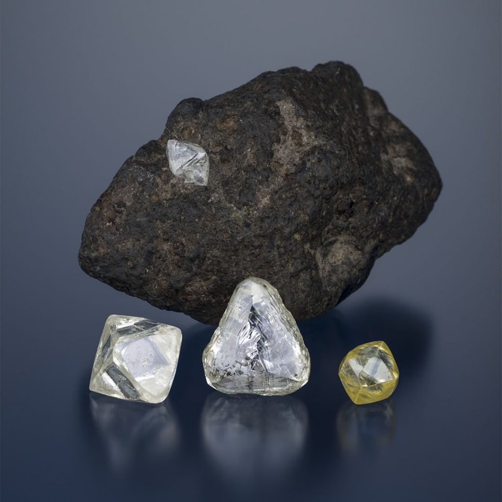 Rough crystals must be cut and polished to produce a finished diamond. Rough diamond crystals beside a piece of rock