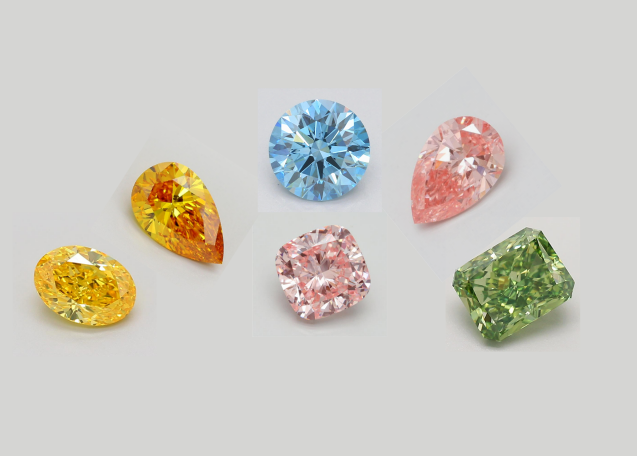Loose pink, blue, yellow and colorless diamonds arranged on a gray background