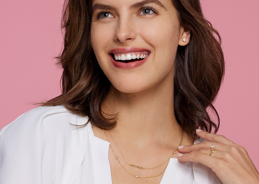 Brilliant Earth model wearing diamond studs, fine necklaces and gold rings
