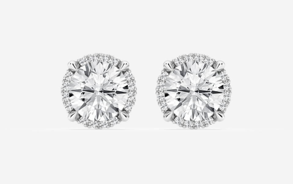 Round diamond studs surrounded by small hidden-halo diamonds in white metal
