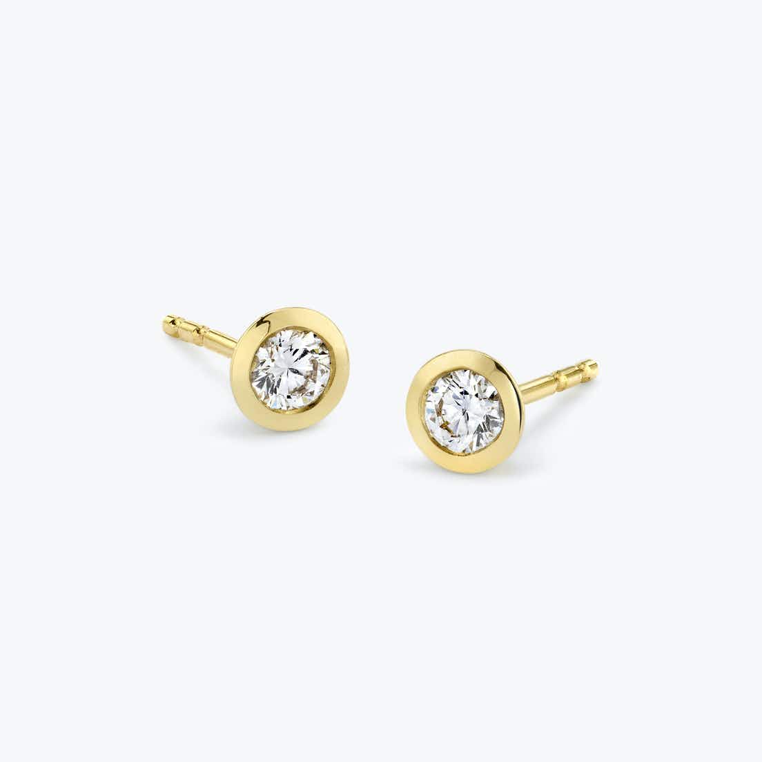 Two small round diamonds surrounded by smooth yellow-gold bezel rims