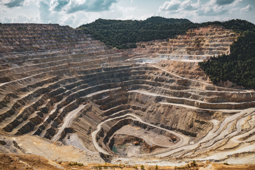 Terraced open-pit mine cut into a forested landscape