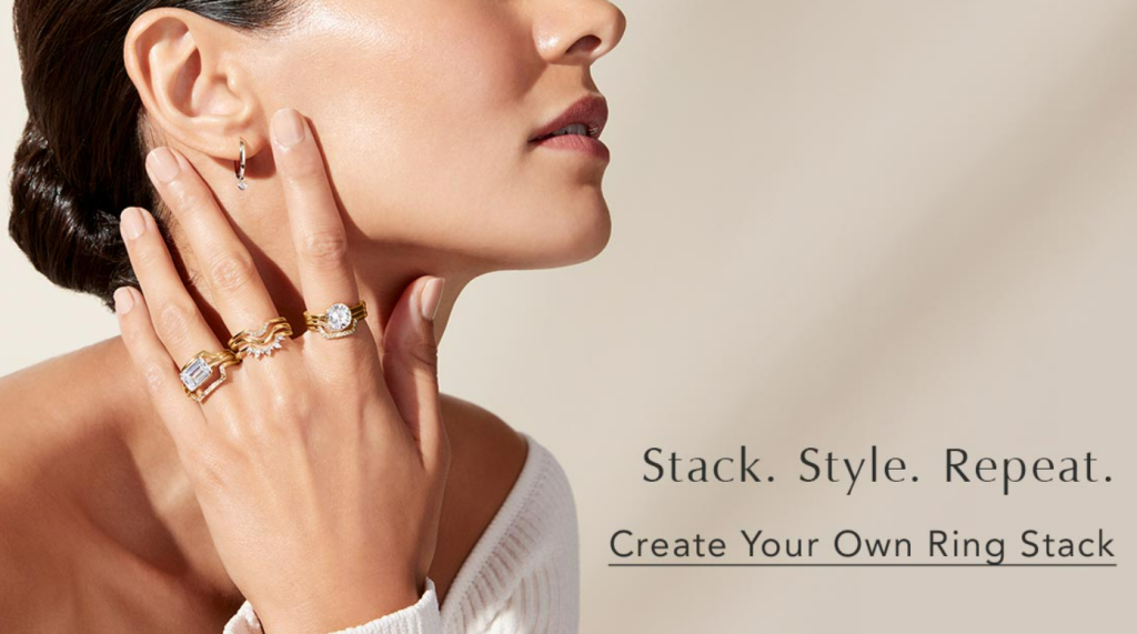 Several yellow-gold diamond rings stacked on a model’s hand