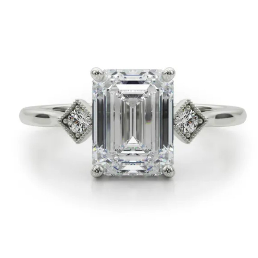 Emerald-cut center with small geometric diamond shoulders on a white-metal ring