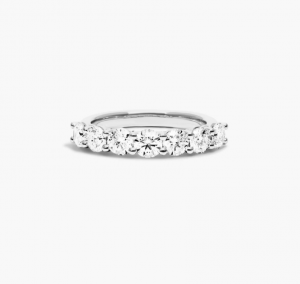 Seven round diamonds across a low white-metal anniversary ring