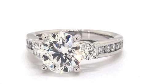 Large round center diamond between two side stones on a diamond-set white-metal band