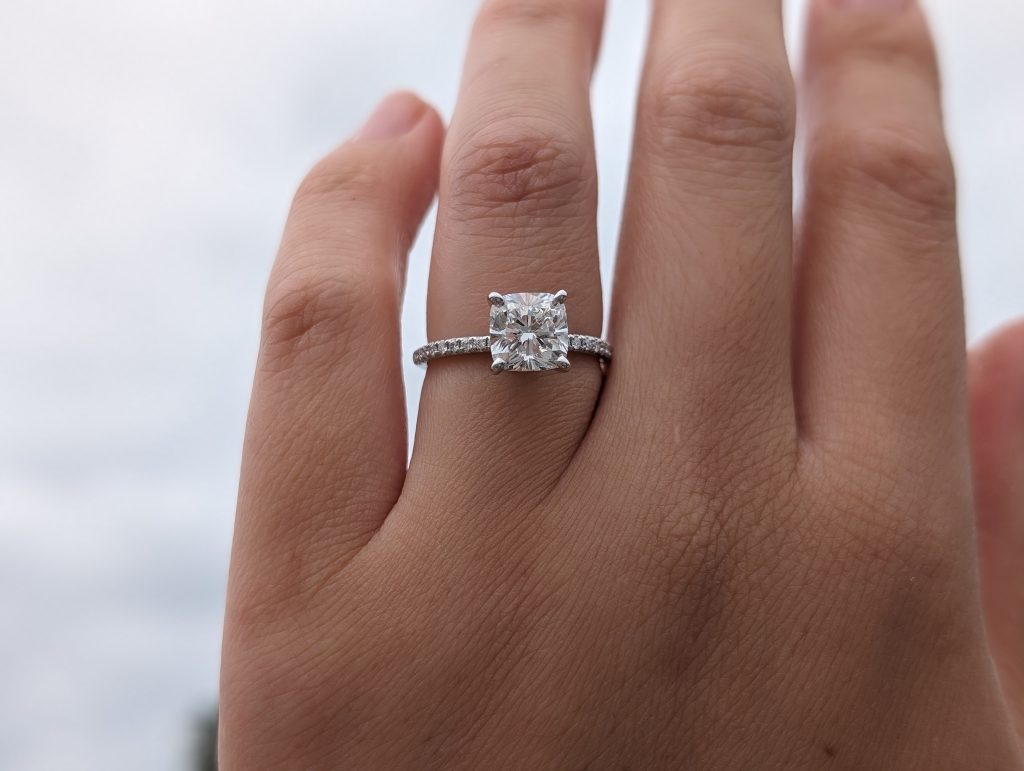1.85 carat cushion cut lab-grown diamond engagement ring in pavé setting worn on hand.
