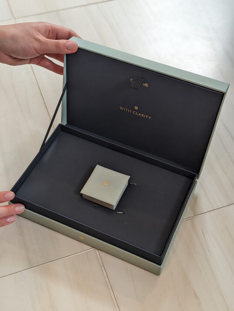 Premium blue engagement ring box from With Clarity shown closed inside branded packaging.